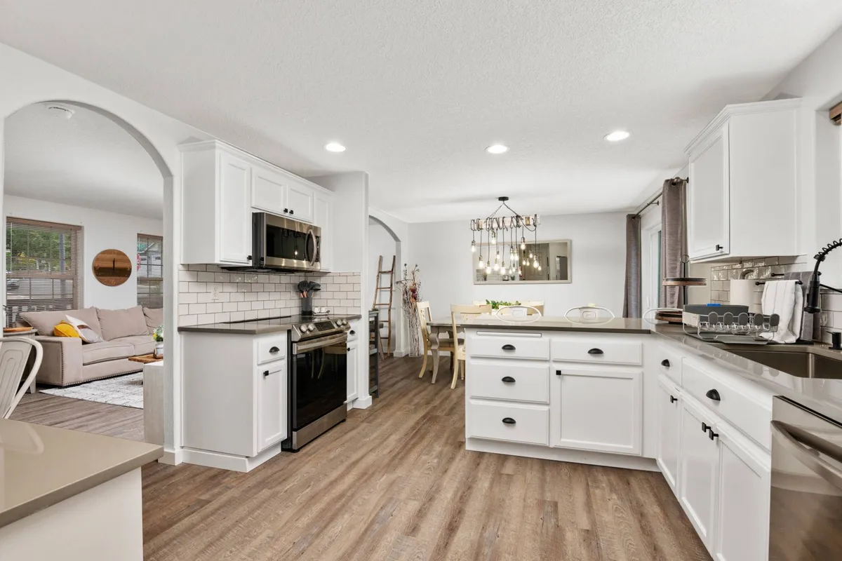A wide-angle view of the open-concept kitchen and dining area. The image highlights the seamless transition from a spacious kitchen with an island and stainless steel appliances to an inviting dining area, ideal for hosting meals and group activities.