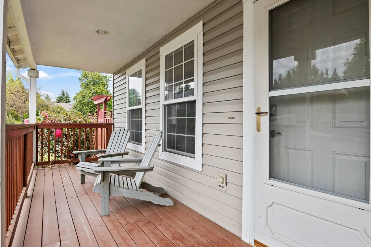 An inviting shot of the front porch, complete with wooden rocking chairs, a charming railing, and the home's doorway. The atmosphere is calm and welcoming, perfect for leisurely mornings or relaxing evenings after a walk.
