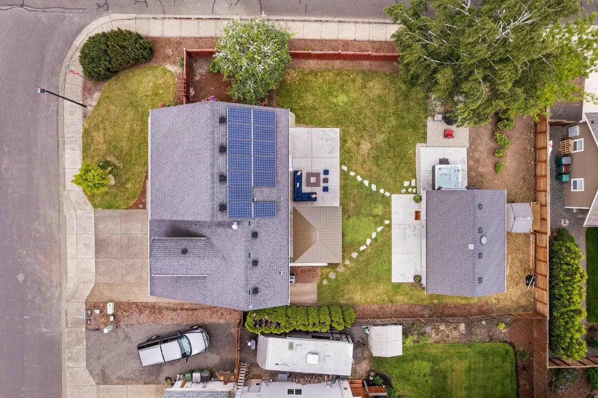 A sunny exterior view showing a row of homes with solar panels, manicured lawns, an inviting patio area with seating, and a welcoming pathway. The setting suggests easy access to outdoor recreation and neighborly exploration, connecting the property to its broader Dundee neighborhood.